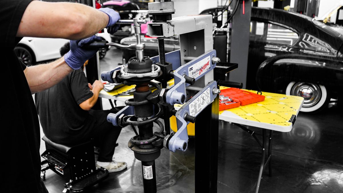 Mechanics repairing vehicles inside a working car garage, where an AI receptionist can answer incoming MOT and service enquiries